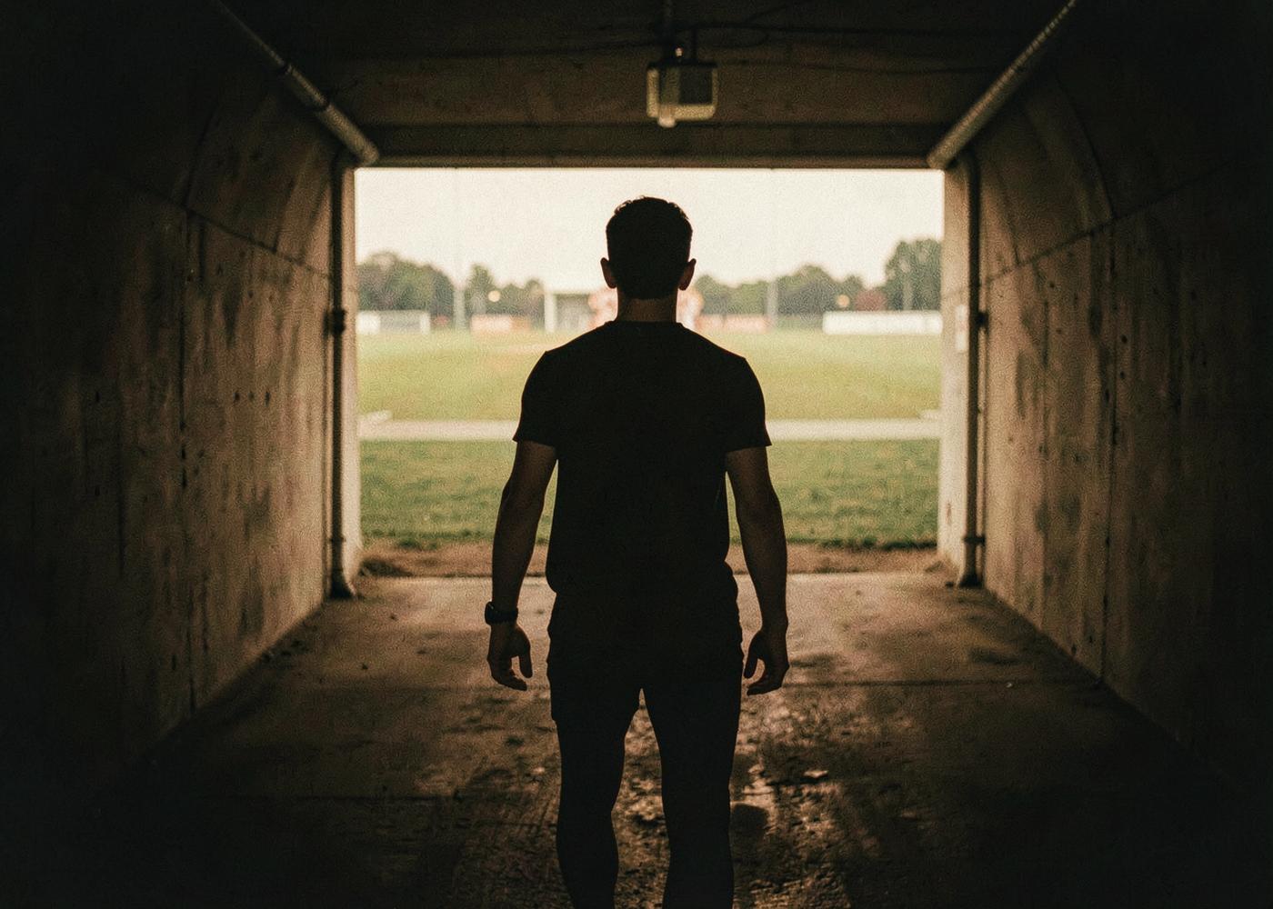 Un sportif de dos dans un tunnel sombre avant d'entrer sur le terrain